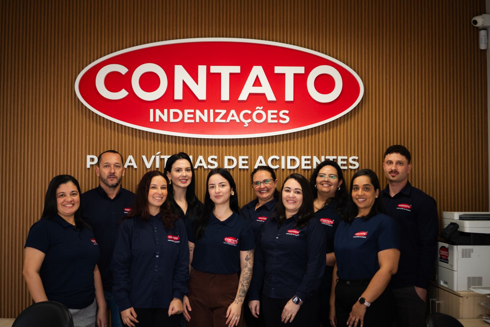 Equipe da Contato Indenizações reunida em frente ao letreiro da empresa